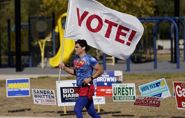 A jogger carries a Vote! flag as he passes a polling station, Tuesday, November 3, 2020, in San Antonio. (Photo by Eric Gay/AP Photo)