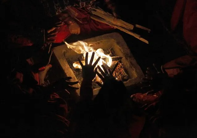 The hand of a devotee is silhouetted as she sits beside a fire to keep warm before taking a holy bath in Saali River on the first day of the Swasthani Brata Katha festival at Sankhu in Kathmandu January 5, 2015. (Photo by Navesh Chitrakar/Reuters)