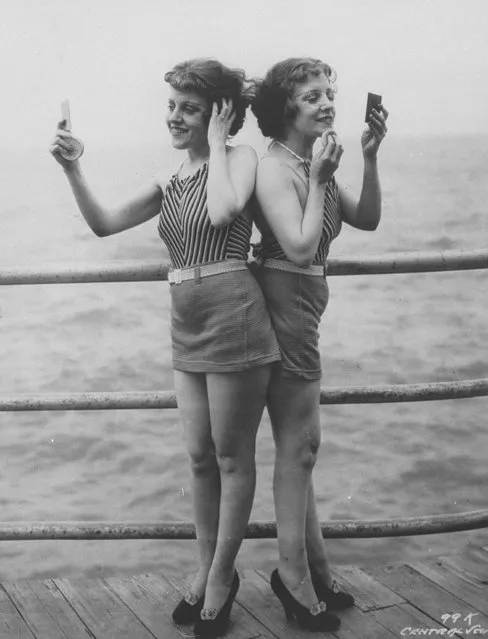 Siamese twins Violet & Daisy Hilton standing back-to-back looking in hand mirrors and powdering faces on pier at Atlantic City, 1946. (Photo by Underwood And Underwood/The LIFE Images Collection/Getty Images)