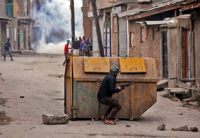 An Indian policeman hides behind a garbage bin during an anti-India protest in Srinagar, November 4, 2016. (Photo by Danish Ismail/Reuters)