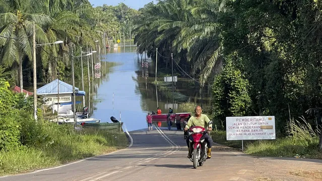 A main road is blocked by flood water at Lengga town in Johor state, Malaysia, Tuesday, March 7, 2023. Malaysian police have found the body of a young woman trapped in a car that was swept away by rushing waters, the fifth death of seasonal floods that have also forced more than 43,000 people to flee their homes. (Photo by AP Photo/Stringer)