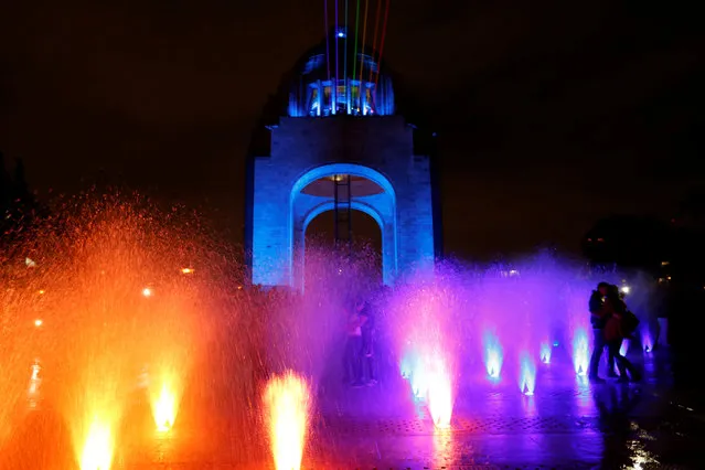 A couple kiss as rainbow-colored laser lights are seen projected from the Revolution Monument across the city center during the International Festival of Lights in Mexico City, Mexico November 11, 2016. (Photo by Carlos Jasso/Reuters)