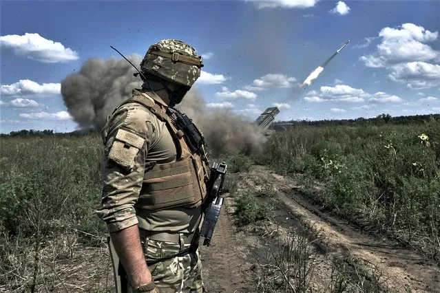 A Ukrainian soldier watches a Grad multiple launch rocket system firing shells with flyers near Bakhmut, Donetsk region, Ukraine, Sunday, August 13, 2023. (Photo by Libkos/AP Photo)