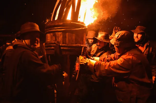 Men from the Clavie Crew carry a burning barrel on the top of a pole packed with tar soaked sticks on January 11, 2016 in Burghead, Scotland. The burning of the Clavie takes place on January 11th each year as local people welcome in the New Year with a fire ceremony which has ancient roots dating back to before1750, and is believed to bring good luck for the coming year. (Photo by Jeff J Mitchell/Getty Images)