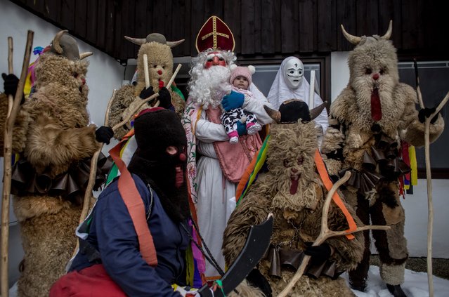 Participants dressed in traditional devil costumes, St. Nicholas and grim reapers pose with child as they walk from house to house during the traditional St. Nicholas parade on December 3, 2016 in village of Francova Lhota, Czech Republic. (Photo by Matej Divizna/Getty Images)