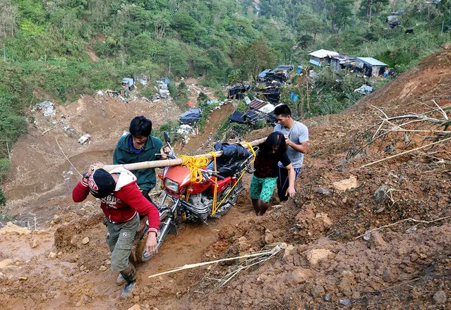 Residents carry a motorcycle as they hike on a road eroded by a landslide caused by Typhoon Mangkhut at a small-scale mining camp in Itogon, Benguet, in the Philippines, September 19, 2018. (Photo by Harlington Palangchao/Reuters)