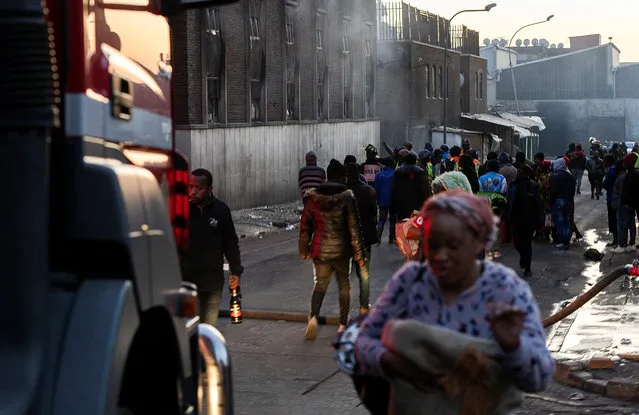 People walk past a building after a deadly blaze in the early hours of the morning, in Johannesburg, South Africa on August 31, 2023. (Photo by Shiraaz Mohamed/Reuters)