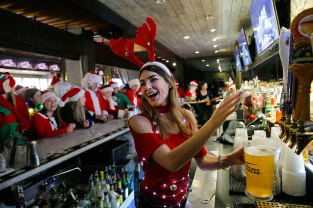 A bartender in festive costume pours beer at Ainsworth Park, the first bar stop in a traditional pub crawl for Santa Con in New York, New York, USA, 10 December 2016. The annual event, is held in several cities around the world and involves people in costumes traveling from bar to bar. (Photo by Peter Foley/EPA)
