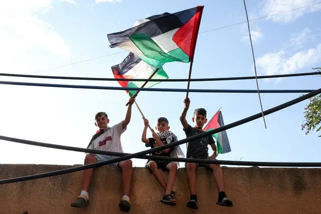 Children hold flags as Palestinian refugees attend a rally to express solidarity with Palestinians in Gaza, in the Burj al-Barajneh refugee camp in Beirut, Lebanon on October 11, 2023. (Photo by Emilie Madi/Reuters)