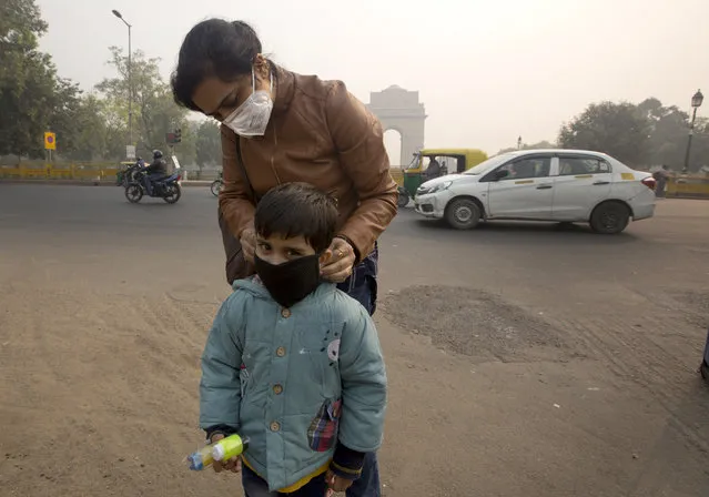 An Indian mother puts a mask to her son a day after Diwali festival in New Delhi, India, Thursday, November 8, 2018. Toxic smog shrouds the Indian capital as air quality falls to hazardous levels with tens of thousands of people setting off massive firecrackers to celebrate the major Hindu festival of Diwali on Wednesday night. (Photo by Manish Swarup/AP Photo)