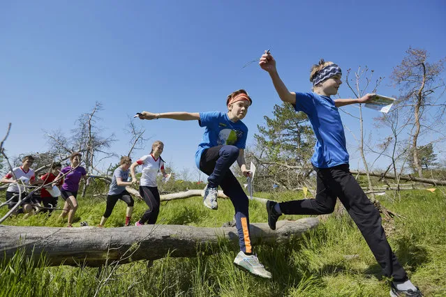 Participants jump over a trunk during an orienteering contest on May 4, 2021 in Kherson, Ukraine. Children and teenagers take part in an orienteering contest on the banks of the Dnieper River. The navigational sport is the first event organized since the coronavirus restrictions were recently eased. The Dnieper River is the main source of water for the region and Russia-annexed Crimea. (Photo by Pierre Crom/Getty Images)
