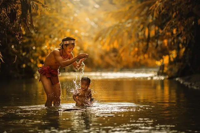 A Mentawai warrior washes a young child in the river on July 19, 2014 on the Mentawai Islands, Indonesia. (Photo by Muhamad Saleh Dollah/Barcroft Media)