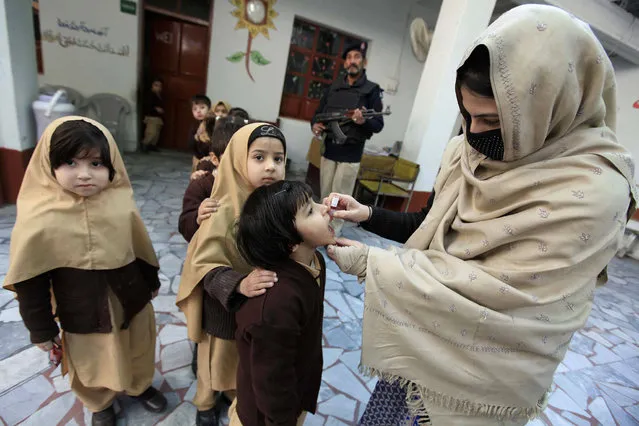 A soldier guards polio vaccination team administering polio vaccination to children during a three-day countrywide vaccination campaign in Peshawar, Pakistan, 21 December 2016. Pakistan is one of the last two countries, along with Afghanistan, where polio is still endemic. Though new polio cases dropped to a nine-year low in 2016, attacks by Islamist militants against health workers and police guarding them remained a challenge for a UN-funded vaccination campaign. (Photo by Arshad Arbab/EPA)