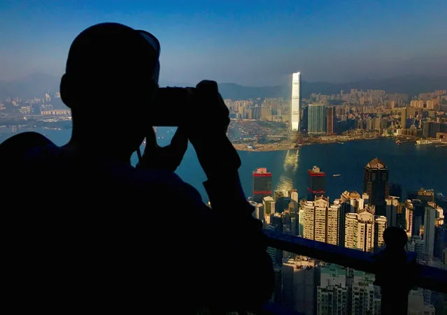 A visitor to Victoria Peak takes photographs of buildings on Hong Kong Island and Kowloon in China, December 9, 2016. (Photo by David Gray/Reuters)
