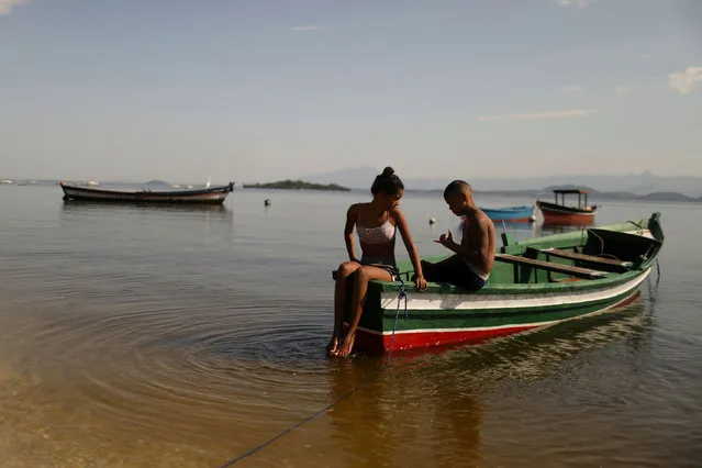 Youths rest on a boat in Paqueta island during the mass vaccination against the coronavirus disease (COVID-19), part of the “Paqueta vacinada” (Paqueta vaccinated) project, that aims to vaccinate the whole population over 18-years-old, in the Guanabara Bay in Rio de Janeiro, Brazil June 20, 2021. (Photo by Pilar Olivares/Reuters)