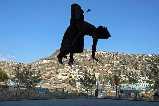 An Afghan youth jumps on a trampoline at the Kart-e-Sakhi cemetery in Kabul on October 17, 2023. (Photo by Wakil Kohsar/AFP Photo)