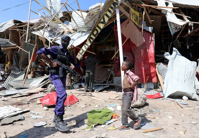 A Somali security officer walks past a child as he secures the scene of an explosion at a market in Wadajir district in Mogadishu, Somalia on November 26, 2018. (Photo by Feisal Omar/Reuters)