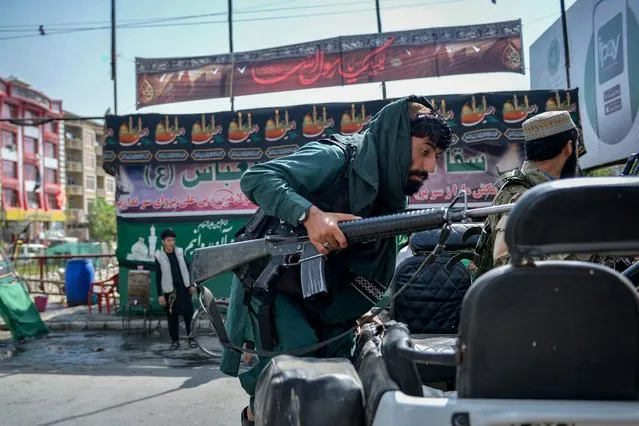 A Taliban fighter clibms up on a vehicle along a makeshift tent where the Shiite Muslims distribute sherbet to people during the Ashura procession which is held to mark the death of Imam Hussein, the grandson of Prophet Mohammad, along a road in Kabul on August 19, 2021, amid the Taliban's military takeover of Afghanistan. (Photo by Hoshang Hashimi/AFP Photo)
