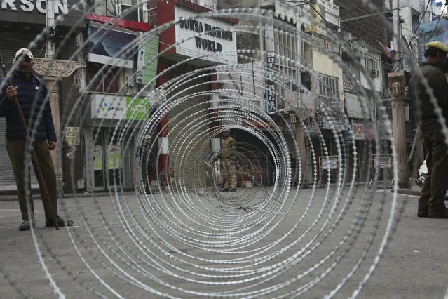 Indian police men keep vigil next to a barbed wire fencing during the third day of curfew in Jammu, India, Sunday, February 17, 2019. The Indian army staged flag marches in sensitive localities, a day after violence was reported during protests against the Pulwama terror attack in which at least 40 soldiers were killed, officials said. (Photo by Channi Anand/AP Photo)