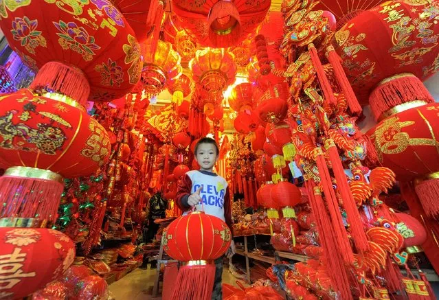A boy holding a lantern walks out from a store selling Spring Festival decorations in Haikou, Hainan province, China, January 21, 2017. (Photo by Reuters/Stringer)