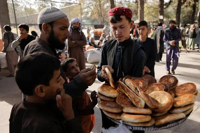 A boy sells bread at a makeshift shelter for displaced Afghan families, who are fleeing the violence in their provinces, at Shahr-e Naw park, in Kabul, Afghanistan October 4, 2021. (Photo by Jorge Silva/Reuters)