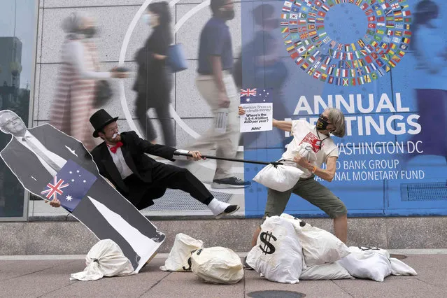 Activists holding a cardboard cutouts of Australian Prime Minister Scott Morrison protest outside of the International Monetary Fund headquarters during the World Bank/IMF Annual Meetings in Washington, Wednesday, October 13, 2021. (Photo by Jose Luis Magana/AP Photo)