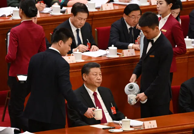 Workers replenish Chinese President Xi Jinping’s teacups during the opening session of the National People's Congress (NPC) at the Great Hall of the People in Beijing on March 5, 2024. (Photo by Greg Baker/AFP Photo)