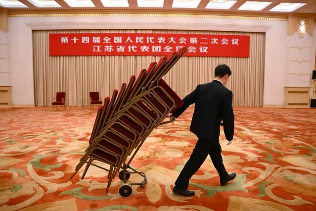 A worker hauls a stack of chairs after the Jiangsu province delegation meeting at the National People's Congress at the Great Hall of the People in Beijing on March 7, 2024. (Photo by Greg Baker/AFP Photo)