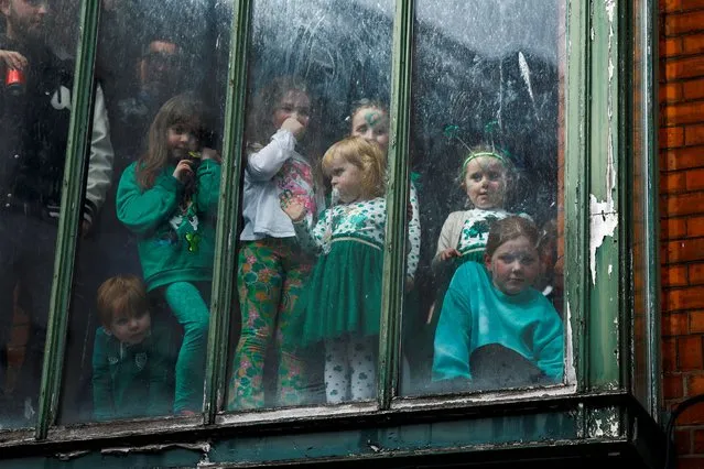 Children look out of a window during the St. Patrick's Day parade in Dublin, Ireland on March 17, 2024. (Photo by Clodagh Kilcoyne/Reuters)