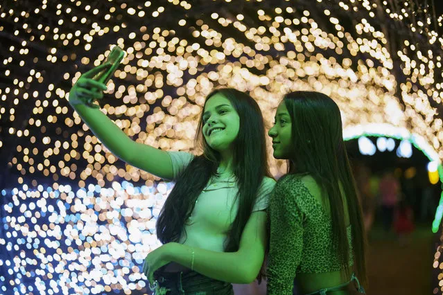 Visitors take a selfie at a Christmas lights event at Ibirapuera park in Sao Paulo, Brazil, Tuesday, December 14, 2021. (Photo by Andre Penner/AP Photo)