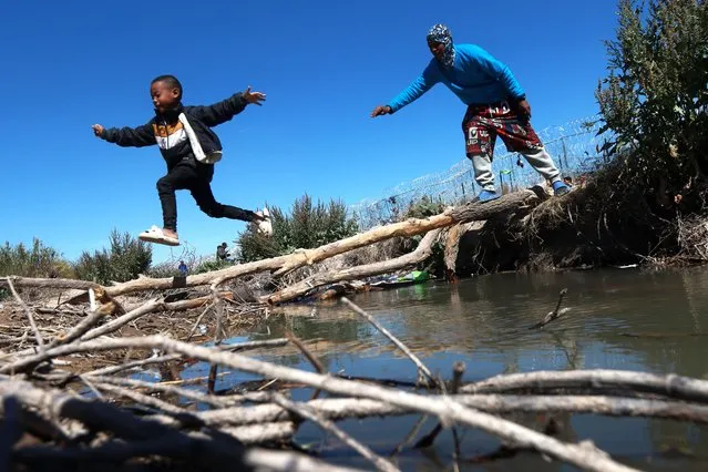 Migrants build their own international bridge at the height of Gate 36 to enter the United States in the vicinity of Gate 36 on the North American side in Ciudad Juarez, Mexico on March 28, 2024. A large number of groups of people are moving to the North American side to apply for asylum. Migrant created a new camp based on wood and other materials that allow them to protect themselves from inclement weather. Consisting of a large number of long trunks that people in mobility now use to pass over the Rio Bravo to the American side without getting wet. (Photo by Christian Torres/Anadolu via Getty Images)