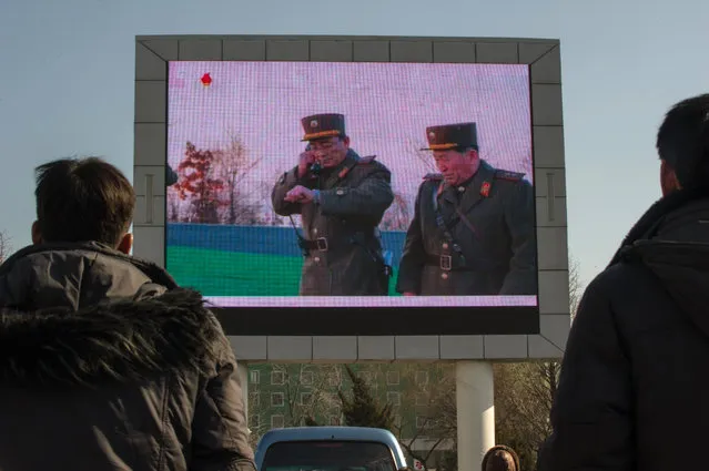 People watch news footage of a missile launch on a giant television screen outside the main railway station in Pyongyang on March 7, 2017. Nuclear-armed North Korea said its missile launches were training for a strike on US bases in Japan, as global condemnation of the regime swelled. (Photo by Kim Won-Jin/AFP Photo)