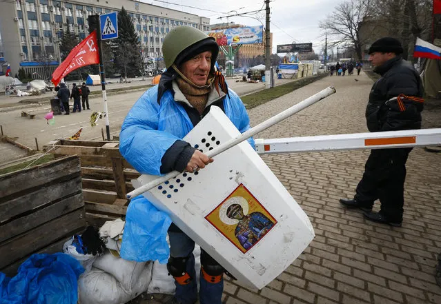 A pro-Russian protester shows his gear at a barricade in front of the seized office of the SBU state security service in Luhansk, in eastern Ukraine April 12, 2014. Ukraine's prime minister offered on Friday to boost local powers in the regions in an effort to undercut pro-Russia separatists who have occupied official buildings in Russian-speaking cities in eastern Ukraine. (Photo by Shamil Zhumatov/Reuters)