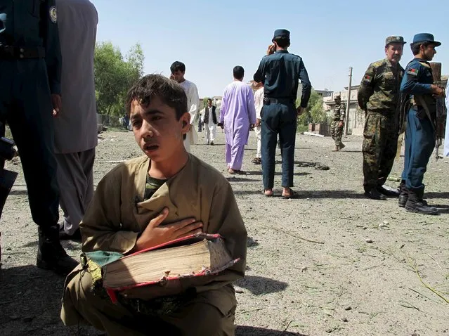 An Afghan boy holds a copy of the Koran at the site of an attack on police headquarters in the provincial capital, Lashkar Gah of the southern Helmand province, Afghanistan, June 30, 2015. At least two civilians died and more than forty were injured during suicide car bomb attack in Lashkar Gah, police said. (Photo by Abdul Malik/Reuters)