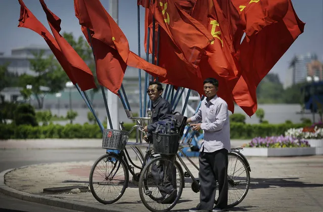 North Korean men wait with their bicycles to cross a street decorated with flags of their ruling Workers' Party Saturday, May 7, 2016 in Pyongyang, North Korea. North Korean leader Kim Jong Un hailed his country's recent nuclear test to uproarious applause as he convened the first full congress of its ruling party since 1980, an event intended to showcase the North's stability and unity in the face of tough international sanctions and deepening isolation. (Photo by Wong Maye-E/AP Photo)