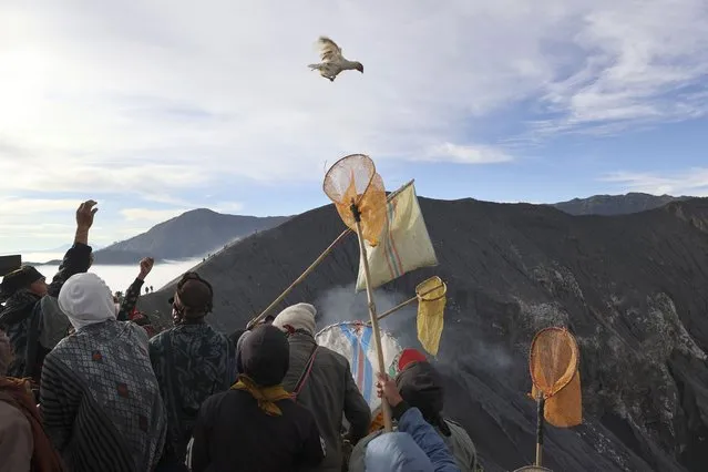 A worshipper throws chicken into the crater of Mount Bromo as an offering to the gods during Yadnya Kasada festival in Probolinggo, East Java, Indonesia, Saturday, June 26, 2021. Every year people gather for the annual festival where offerings of rice, fruit, vegetables, livestock or money are made to Hindu gods at the active volcano to ask for blessings and assure a bountiful harvest. (Photo by Trisnadi/AP Photo)