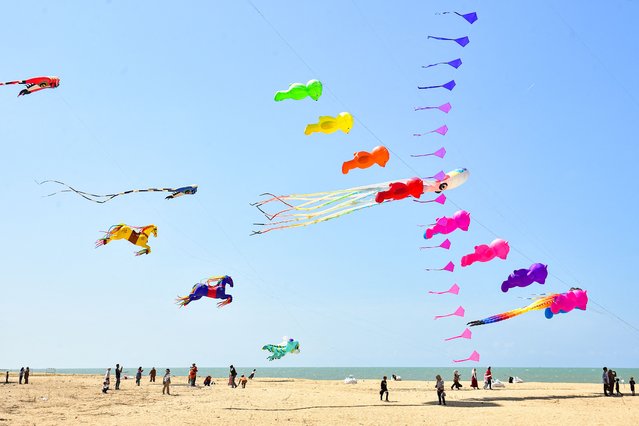 People gather to watch and take photo during a kite festival on Ao Manao Beach in the southern Thai province of Narathiwat on April 15, 2024. (Photo by Madaree Tohlala/AFP Photo)