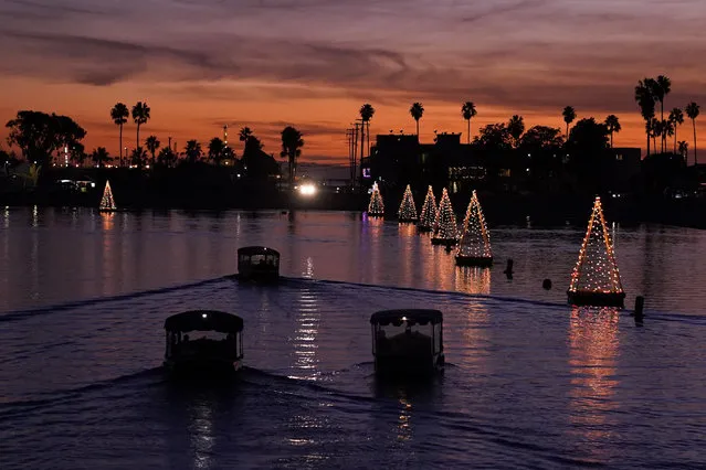 Boats make their way past floating Christmas tree lights on Sunday, December 19, 2021, in Long Beach, Calif. (Photo by Ashley Landis/AP Photo)