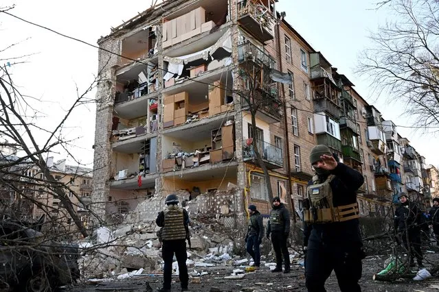 Ukrainian policemen secure the area by a five-storey residential building that partially collapsed after a shelling in Kyiv on March 18, 2022, as Russian troops try to encircle the Ukrainian capital as part of their slow-moving offensive. Authorities in Kyiv said one person was killed early today when a downed Russian rocket struck a residential building in the capital's northern suburbs. They said a school and playground were also hit. (Photo by SErgei Supinsky/AFP Photo)
