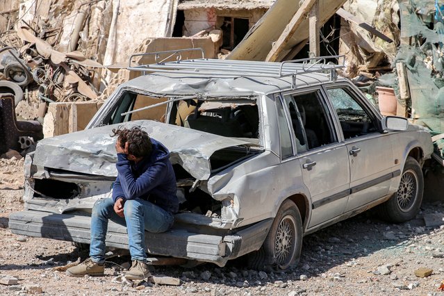 A youth sits by a damaged vehicle outside a destroyed building in the aftermath of an overnight Israeli airstrike on the city of Baalbek in east central Lebanon on March 12, 2024. Israeli air strikes on March 11 near Lebanon's eastern city of Baalbek killed one person, in the second raid on the Hezbollah stronghold since cross-border hostilities began. The Israeli military confirmed its jets had hit two sites belonging to “Hezbollah's aerial forces” in retaliation for strikes on the occupied Golan Heights over several days. (Photo by AFP Photo)