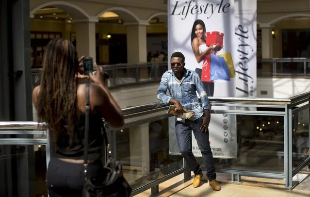 Ted Odhiambo, who said he used to work in one of the mall's shops, poses while his friend takes a photograph of him in the reopened Westgate Shopping Mall, nearly two years after a terrorist attack there left at least 67 people dead, in the capital Nairobi, Kenya Saturday, July 18, 2015. Hundreds of shoppers thronged through the reopened mall Saturday, following two years of repairs after security forces battled four gunmen from Somalia's al-Qaida-linked al-Shabab militant group there in September 2013. (Photo by Ben Curtis/AP Photo)