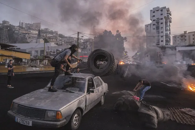 Protesters unload tyres from a car which they'll burn to block a highway in Beirut, Lebanon during unrest sparked by economic difficulties on October 18, 2019. Protests flared this week after the government proposed taxing messaging services like Whatsapp, which came on the heels of an unpopular austerity budget passed in July, intended to deal with a ballooning deficit. (Photo by Sam Tarling/Getty Images)