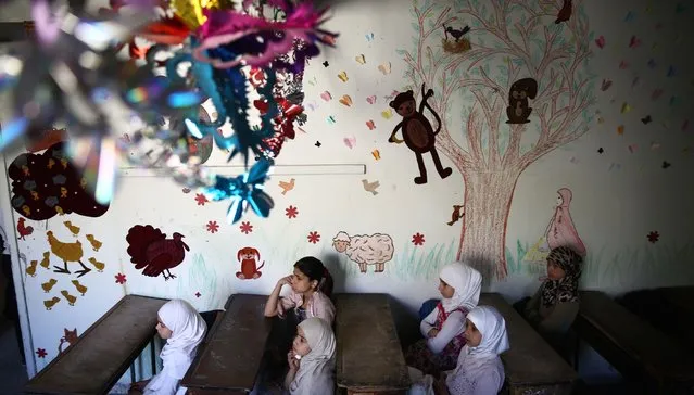 Syrian school girls sit at their classroom at the Saif al-Dawla school as they take part in activities surrounding an art competition organised as part of a local initiative to shift the children's minds from the atrocities of the Syrian war, on May 25, 2016, in the besieged rebel bastion of Douma, a flashpoint near the Syrian capital. (Photo by Abd Doumany/AFP Photo)