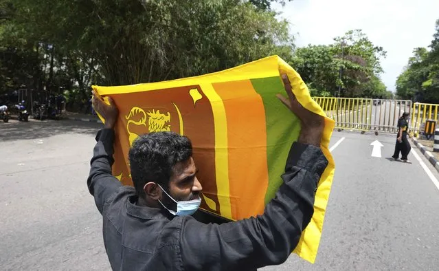 A man holding a national flag protests demanding president Gotabaya Rajapaksa resign in Colombo, Sri Lanka, Tuesday, April 5, 2022. A group of Sri Lankan governing party lawmakers called Tuesday for the appointment of an interim government, warning that a failure to do so would lead to violence and anarchy, as demonstrators continue to demand the resignation of Rajapaksa over the country’s worst economic crisis in decades. (Photo by Eranga Jayawardena/AP Photo)