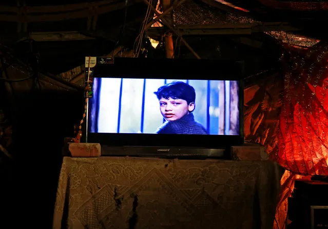 A television plays a movie in a makeshift cinema located under a bridge in the old quarters of Delhi, India May 25, 2016. A makeshift cinema hall under a 140-year-old bridge in the Indian capital is allowing poor rickshaw pullers and migrant labourers to escape daily hardship and sweltering heat into a world of Bollywood song, dance and romance. With the rusty iron floor of the bridge as its ceiling and some old rags acquired on the cheap from a nearby crematorium serving as curtains and floor mats, the cinema shows four films a day. (Photo by Cathal McNaughton/Reuters)