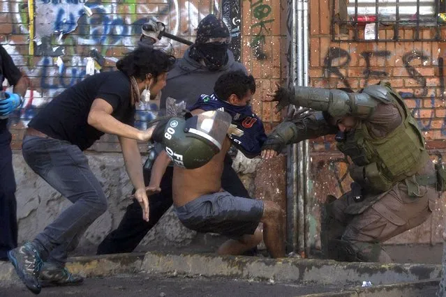 Demonstrators clash with riot police during a protest against the government in Santiago on November 16, 2019. Chile said Friday it will hold a referendum to replace the country's dictatorship-era constitution – a key demand of protesters after nearly a month of violent civil unrest. The announcement sent the stock market soaring over eight percent – the biggest daily rise in a decade – and sparked a recovery by the peso, which was up 3.2 percent. (Photo by Claudio Reyes/AFP Photo)