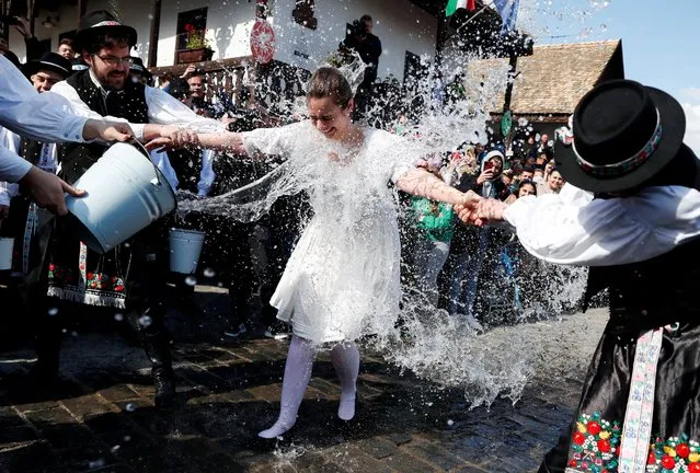 A woman dressed in traditional clothes reacts as men throw water at her during a traditional Easter celebration in Holloko, Hungary, April 18, 2022. (Photo by Bernadett Szabo/Reuters)