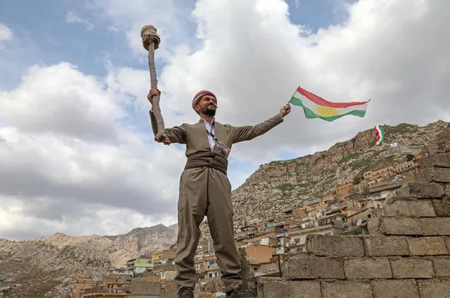 A man waves a Kurdish flag during celebrations of the Persian new year Nowruz (Noruz) in the town of Akra, about 100 kilometres north of Arbil in Iraq's northern autonomous Kurdish region, on March 20, 2022. (Photo by Safin Hamed/AFP Photo)