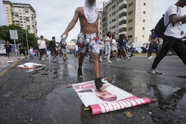 A protester steps on a campaign sign of President Nicolas Maduro during a march against hish being declared the winner of the presidential election, the day after the vote in Caracas, Venezuela, Monday, July 29, 2024. (Photo by Fernando Vergara/AP Photo)