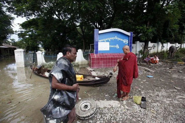 A man walks past as a Buddhist monk waits to ride a boat near a signboard showing Kalay general hospital in Kalay township, northwestern Sagaing region, Myanmar, Sunday, August 2, 2015. Heavy rains in Myanmar have caused more flooding, devastating several townships and forcing more than 18,000 people into temporary shelters, officials said Saturday. (Photo by Khin Maung Win/AP Photo)
